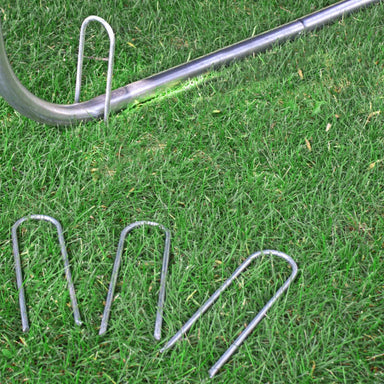 Skywalker Trampoline Wind Stakes lying in the grass - 4 pack