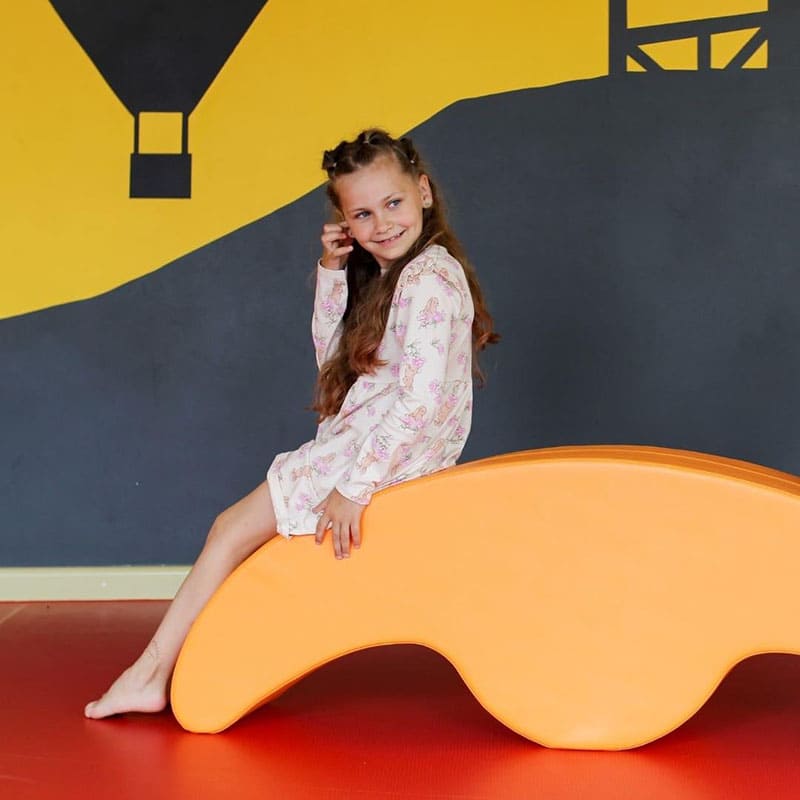 Soft Play rocker in orange with a girl sitting