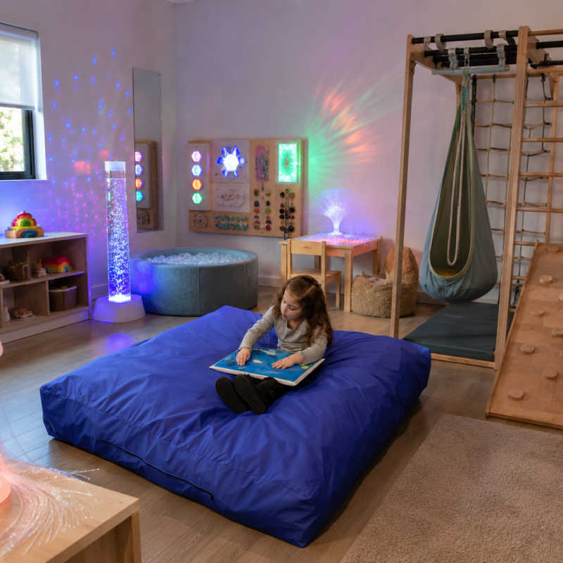 Enabling Devices Crash Pad in a sensory room with calming lights and active play equipment