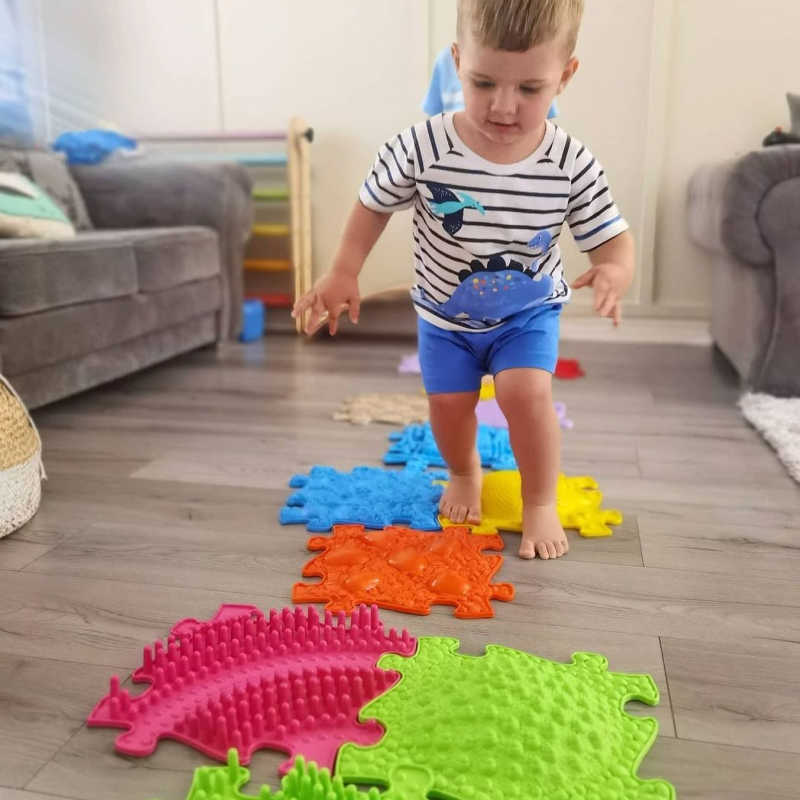 Boy walking on rainbow sensory playmat