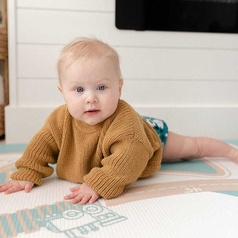 August Rose Sand Shwally Playmat with a baby