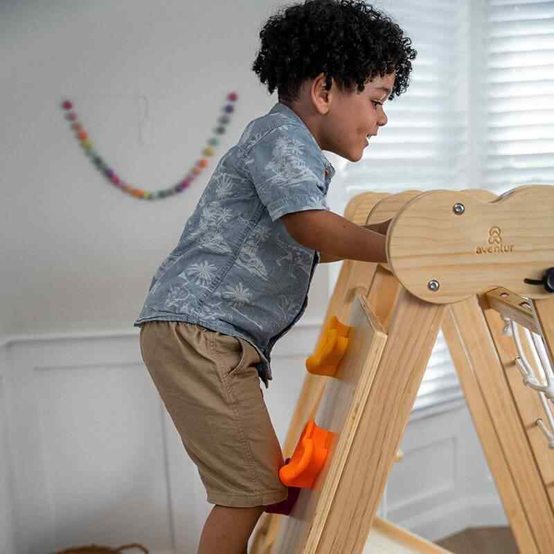 Child climbing the rock wall on the Chestnut 8-in-1 Indoor Jungle Gym