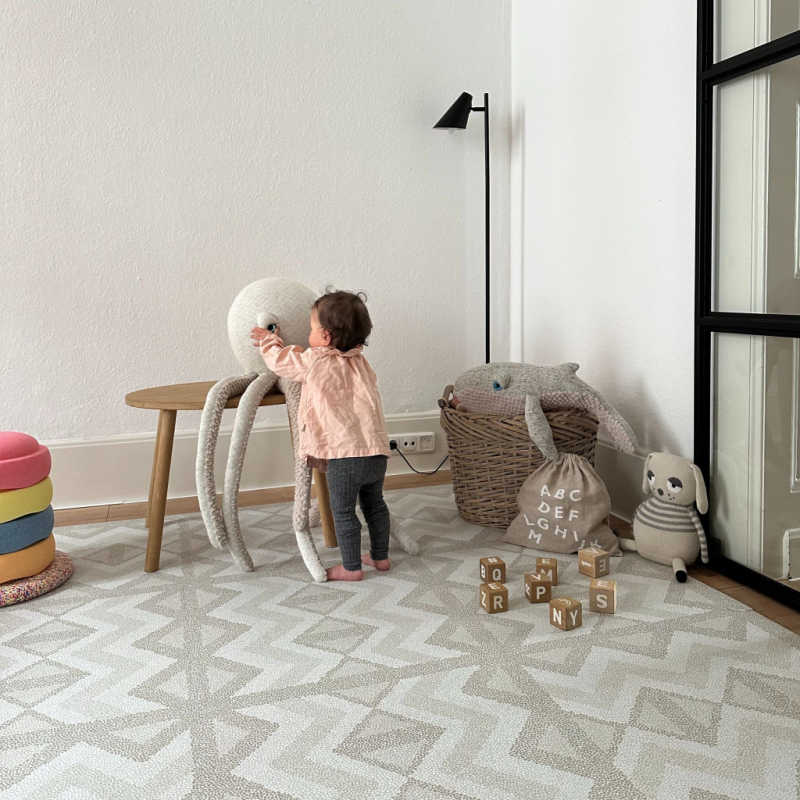 Eeveve Kilim Feather Gray Play Mat in a playroom with a toddler