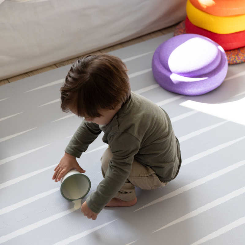 Eeveve Lucio Nordic Mist Play Mat with a kid that spilled milk