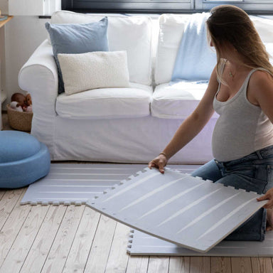 Eeveve Lucio Nordic Mist Play Mat with a mom putting it together