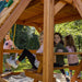 Gorilla Playsets Chateau Standard Wood Roof Far View Showing Kids On A Picnic Table