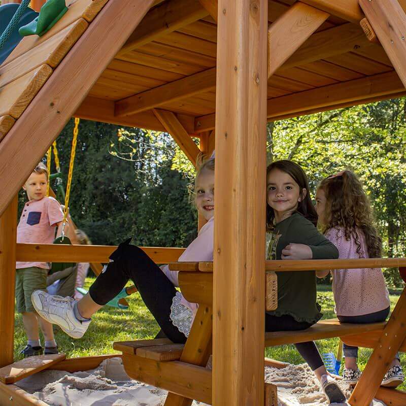 Gorilla Playsets Chateau Standard Wood Roof Far View Showing Kids On A Picnic Table