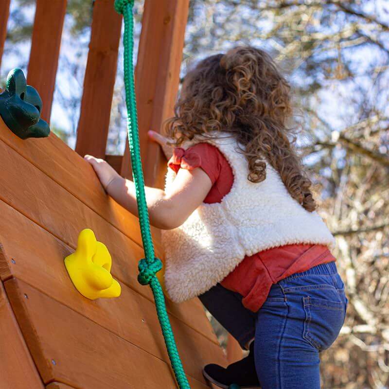 Child climbing rock wall on Gorilla Outing swing set