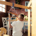 Indoor Wooden Playhouse with Triangle ladder, Slide Board and Swings with a boy playing with gymnastics rings