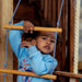 Indoor Wooden Playhouse with Triangle ladder, Slide Board and Swings with a kid playing on the rope ladder