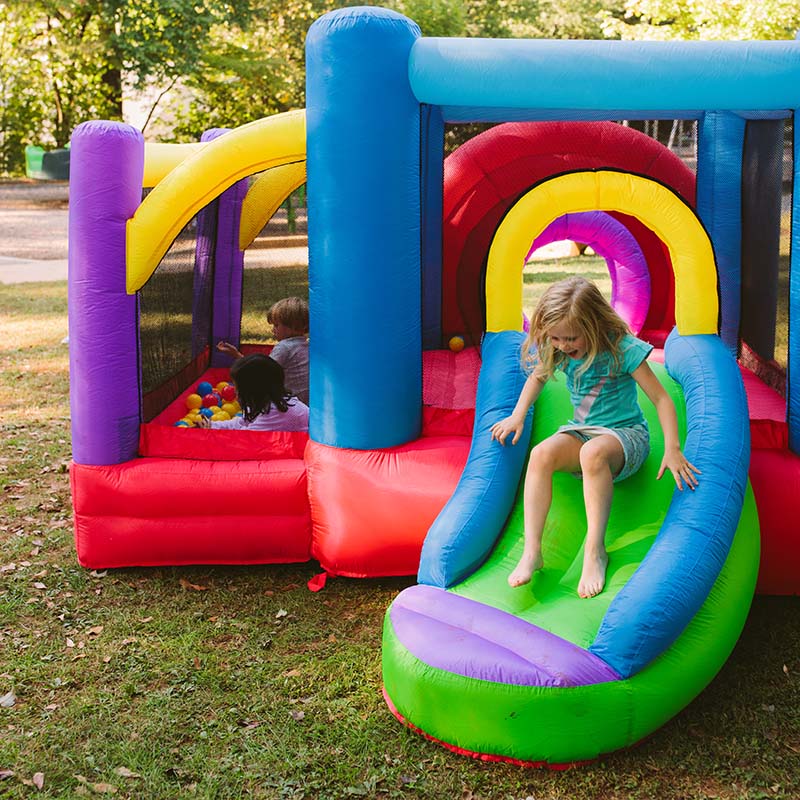 kid-wise-lucky-rainbow-bounce-house-kin-in-green-dress-sliding