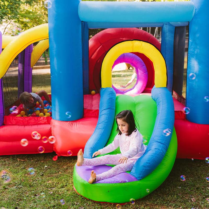 kid-wise-lucky-rainbow-bounce-house-rear-left-side-view-with-kid-sliding
