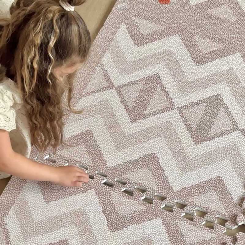 Kilim Play Mat in Soft Clay with girl putting them together