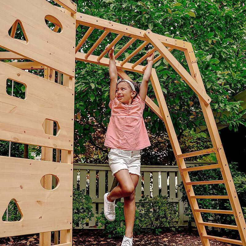 wooden swing set with girl on the monkey bars
