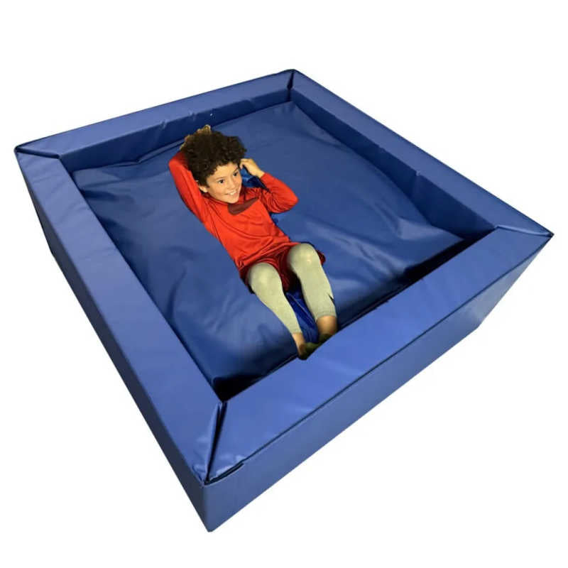 Large blue 5 foot by 5 foot sensory crash pit with a boy resting inside