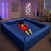 Large blue sensory crash pit in a sensory playroom with therapy equipment