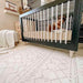 Shwally Enya Double Sided Playmat in a nursery with a baby crib sitting on it. 