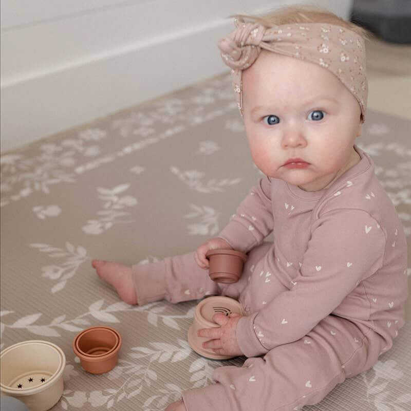 The August Rose Sand Shwally Playmat up close with baby