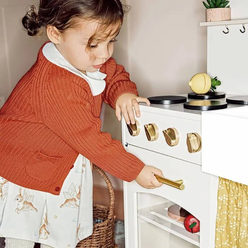 A Little Girl Opening the Oven of Tiny Land Wooden Honey Kitchenett for Kids