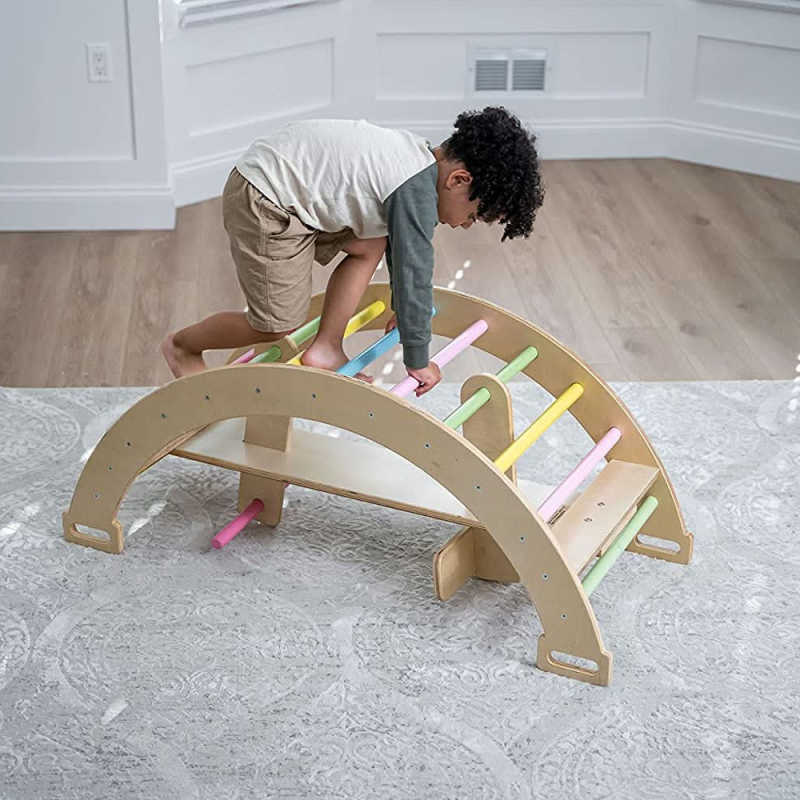 Child using Avenlur Bailis Climbing Arch and Rocker for supervised indoor climbing play