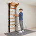 BenchK Wall Bars 211 with a teen standing on a mat and holding a wooden rung beneath the pull-up bar