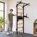 BenchK Wall Bars 222 – Teen standing beside the wall bars and holding a rung, with the dip station visible.