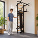 BenchK Wall Bars 223 – Teen standing beside the wall bars with one hand on the frame; dip station and vertically stored bench are visible.