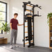 BenchK Wall Bars 233 – Teen standing beside the wall bars with one hand on the frame; dip station and vertically stored bench are visible.