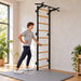 BenchK Wall Bars 721 - teen stretching beside the black frame in a bright home gym