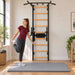 BenchK Wall Bars 722 - teen stretching beside the black frame in a bright home gym