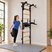 BenchK Wall Bars 732 - teen stretching beside the black frame in a bright home gym