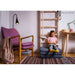 BenchK Folding Gymnastics Mat – child seated on the folded gray mat while reading beside a wooden wall-bar setup