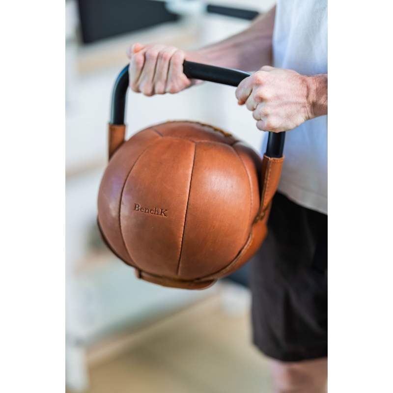 BenchK Leather Kettlebell – person holding the brown leather kettlebell by its metal handle