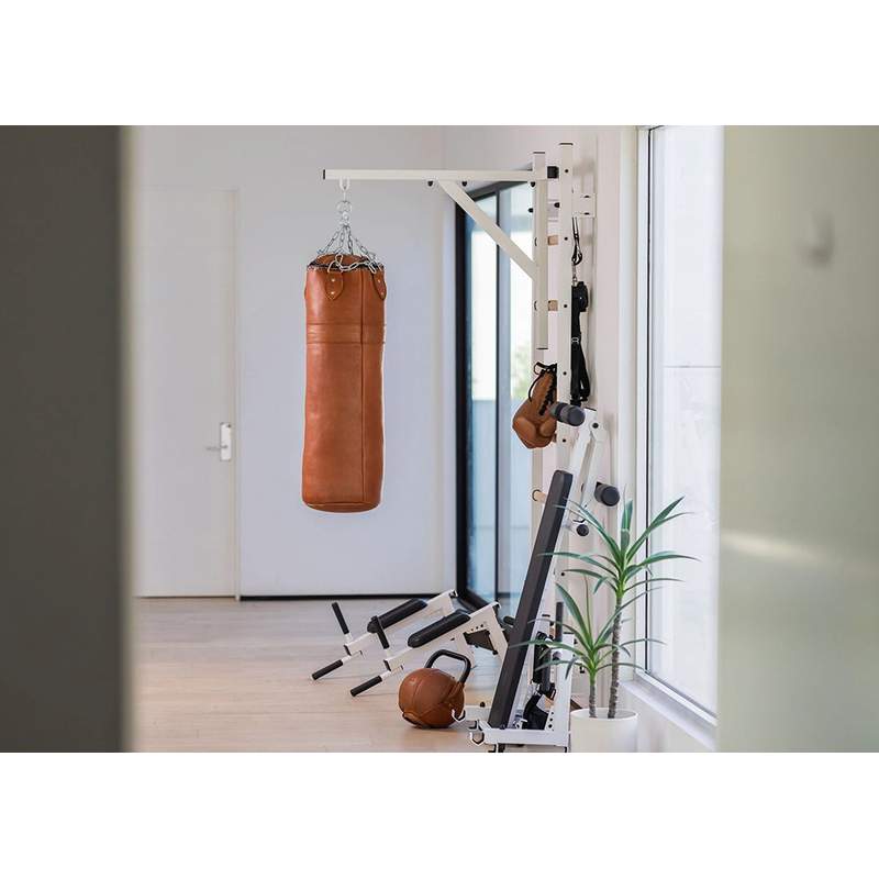 BenchK Leather Punching Bag – brown leather punching bag mounted in a home gym