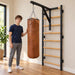 BenchK Leather Punching Bag – Teen standing beside the suspended brown leather bag with one hand resting on its side; bag shown filled, with filling, holder and wall bars sold separately.