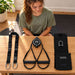 BenchK Recoil S2 Home – Teen inspecting the trainer, two handles, lashing strap and combined carry bag/door mount before training.