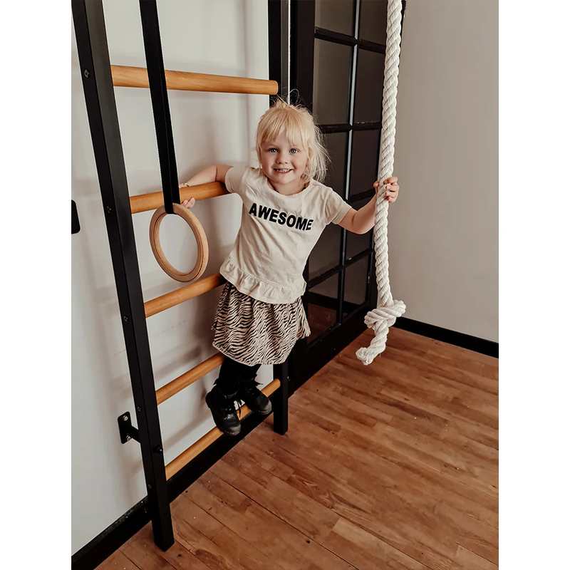 BenchK Wall Bars & Gymnastics Set 221 – child standing on a low rung of the black wall bars, with A076 gymnastics rings and climbing rope visible
