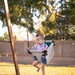 Toddler relaxing in the supportive Bijou Baby Swing outdoors