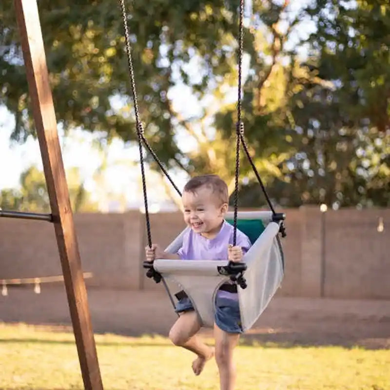 Toddler relaxing in the supportive Bijou Baby Swing outdoors