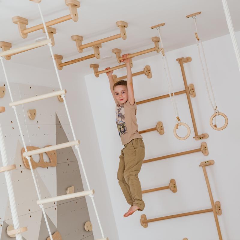 Wood and Hearts Climbing Wall Playground – kid hanging from wall bars
