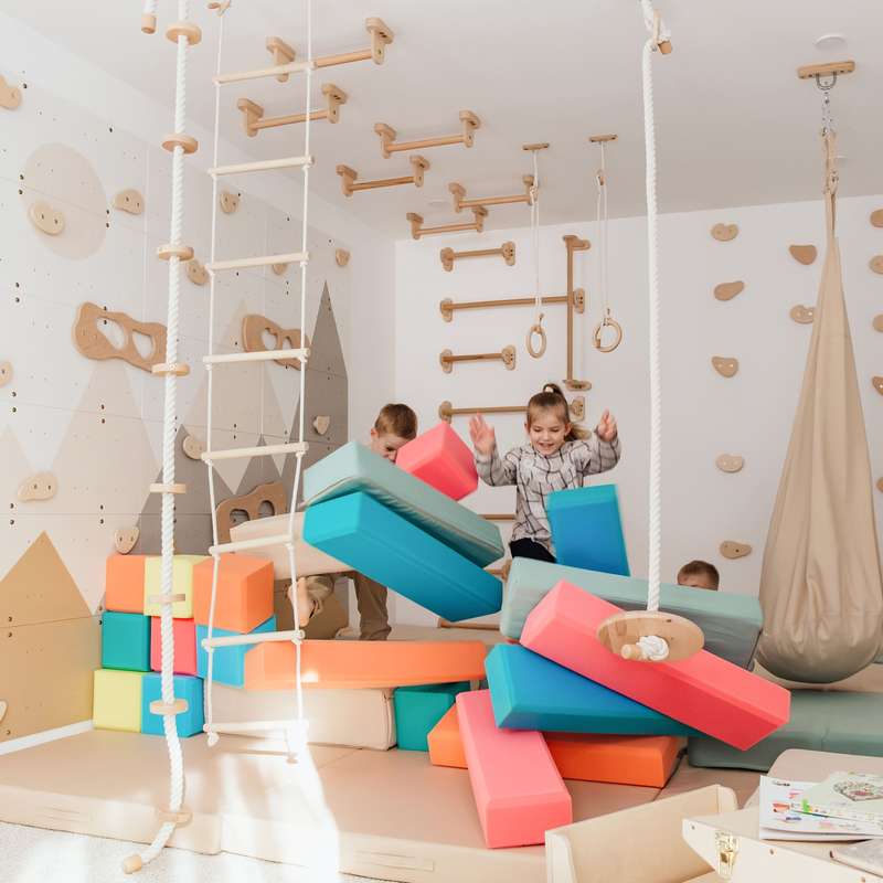 Wood and Hearts Climbing Wall Playground – kids playing with optional foam blocks beside the wall gym