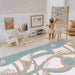 Baby drawing beside the Dakota Ivory Shwally Playmat in a family room