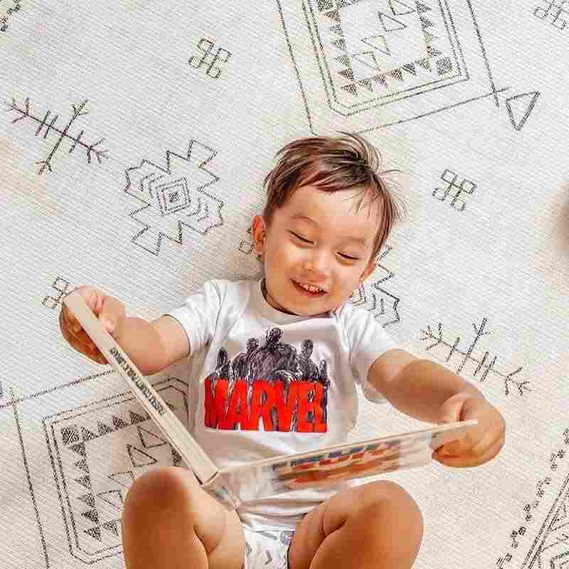 Baby reading on the Dakota Ivory Shwally Playmat viewed from above