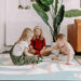 Three kids playing on the illustrated reverse side of the Dakota Ivory Shwally Playmat