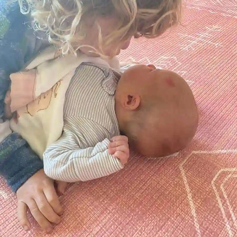 Siblings sharing a quiet moment on the Dakota Rose Shwally Playmat