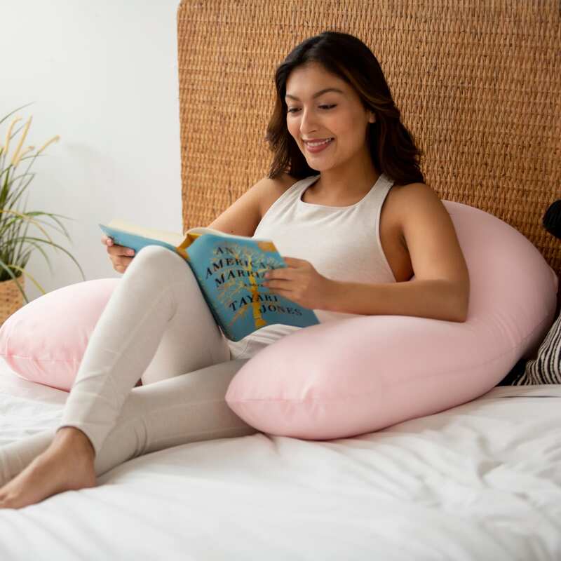 Crescent Backrest – adult reading in bed with a Rose Quartz backrest