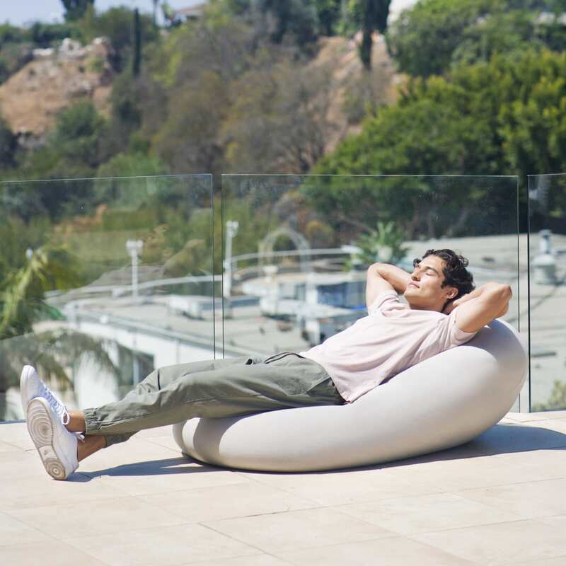 Outdoor Moon Pod – adult reclining on a covered Moon Pod on a patio