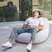 Outdoor Moon Pod – adult relaxing on the covered seat on a paved patio