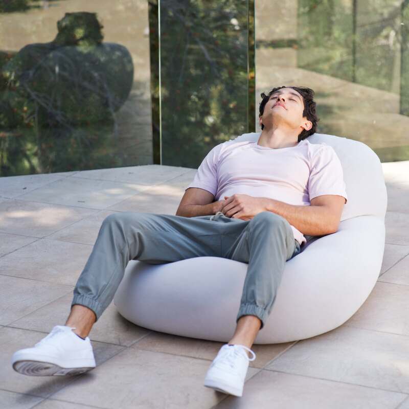 Outdoor Moon Pod – adult relaxing on the covered seat on a paved patio