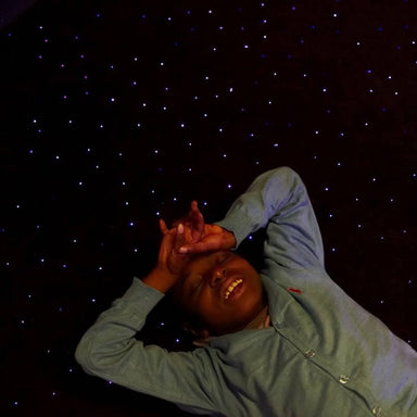 Top view of a child lying on the Experia LED Fiber Optic Carpet